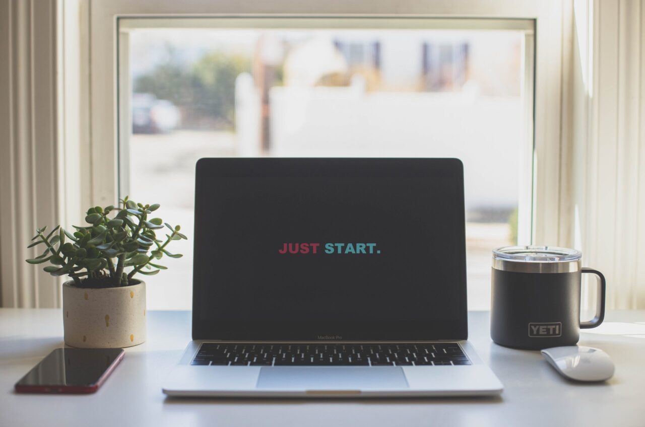 Laptop auf Tisch, auf dem Bildschirm steht nur "just start"