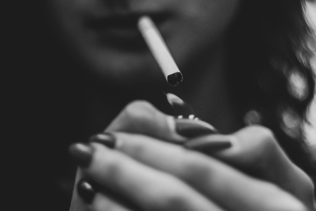 Frau zündet sich Zigarette an, schwarz/weiss
